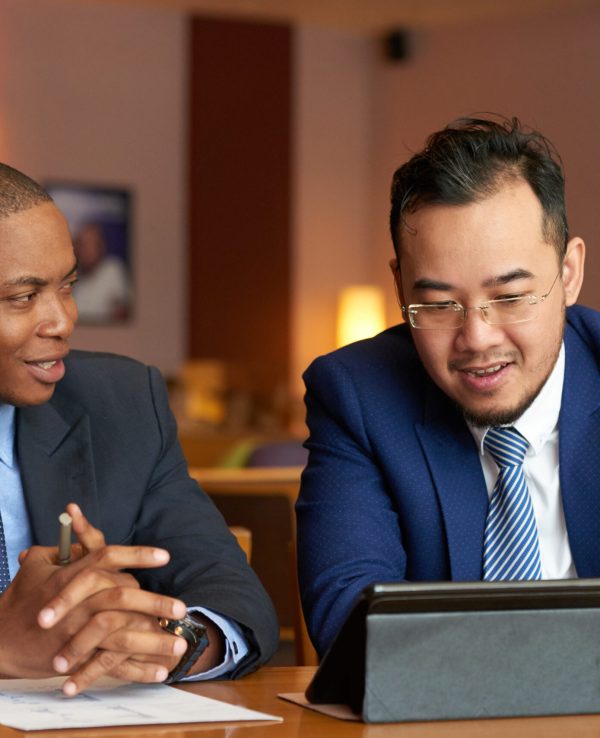 Vietnamese businessman showing information on tablet computer to his coworker at meeting
